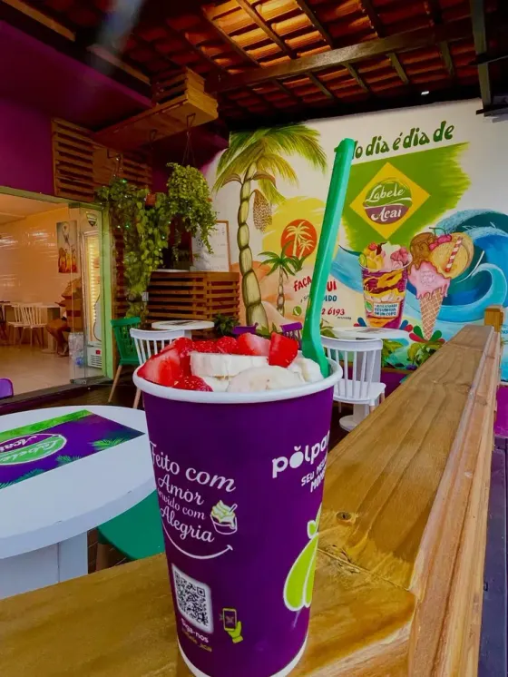 Copo roxo da Labele com morango no balcão de madeira
